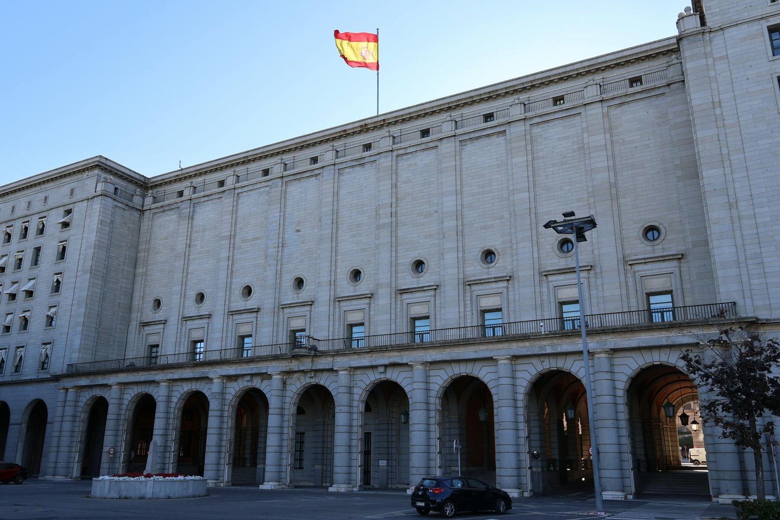 Exterior of a historic government building in Spain with a Spanish flag atop.