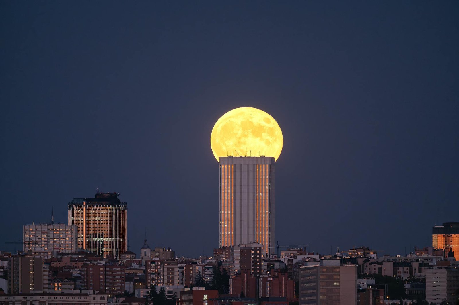Stunning full moon rising above the skyscrapers of Madrid, Spain at night.