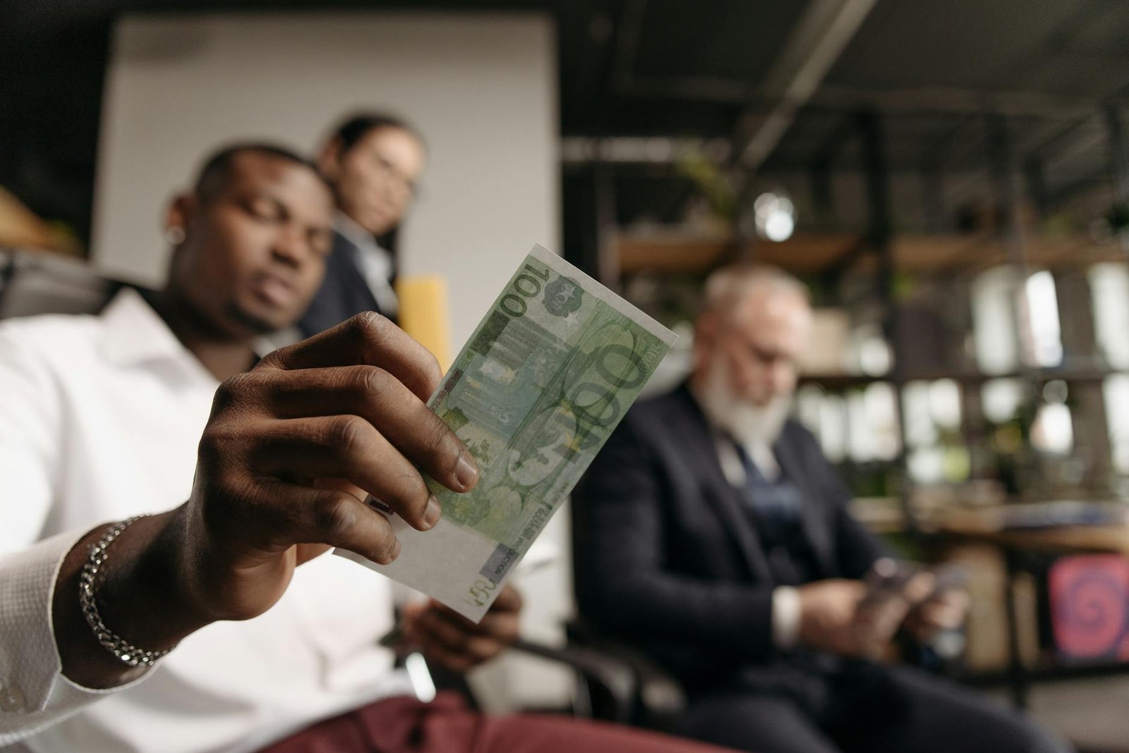 Colleagues in business attire handling currency in a modern office setting.