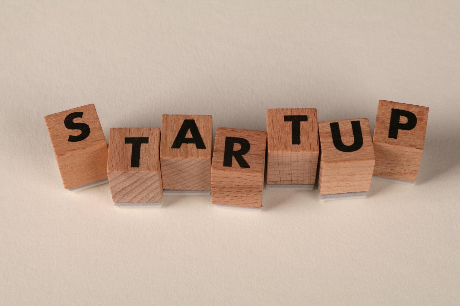 Wooden blocks forming the word 'STARTUP' on a neutral background, symbolizing new business ventures.
