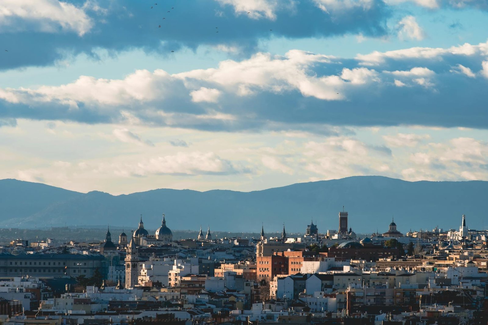 Elevated view of Madrid's urban skyline with iconic architecture and a dramatic cloudy sky.