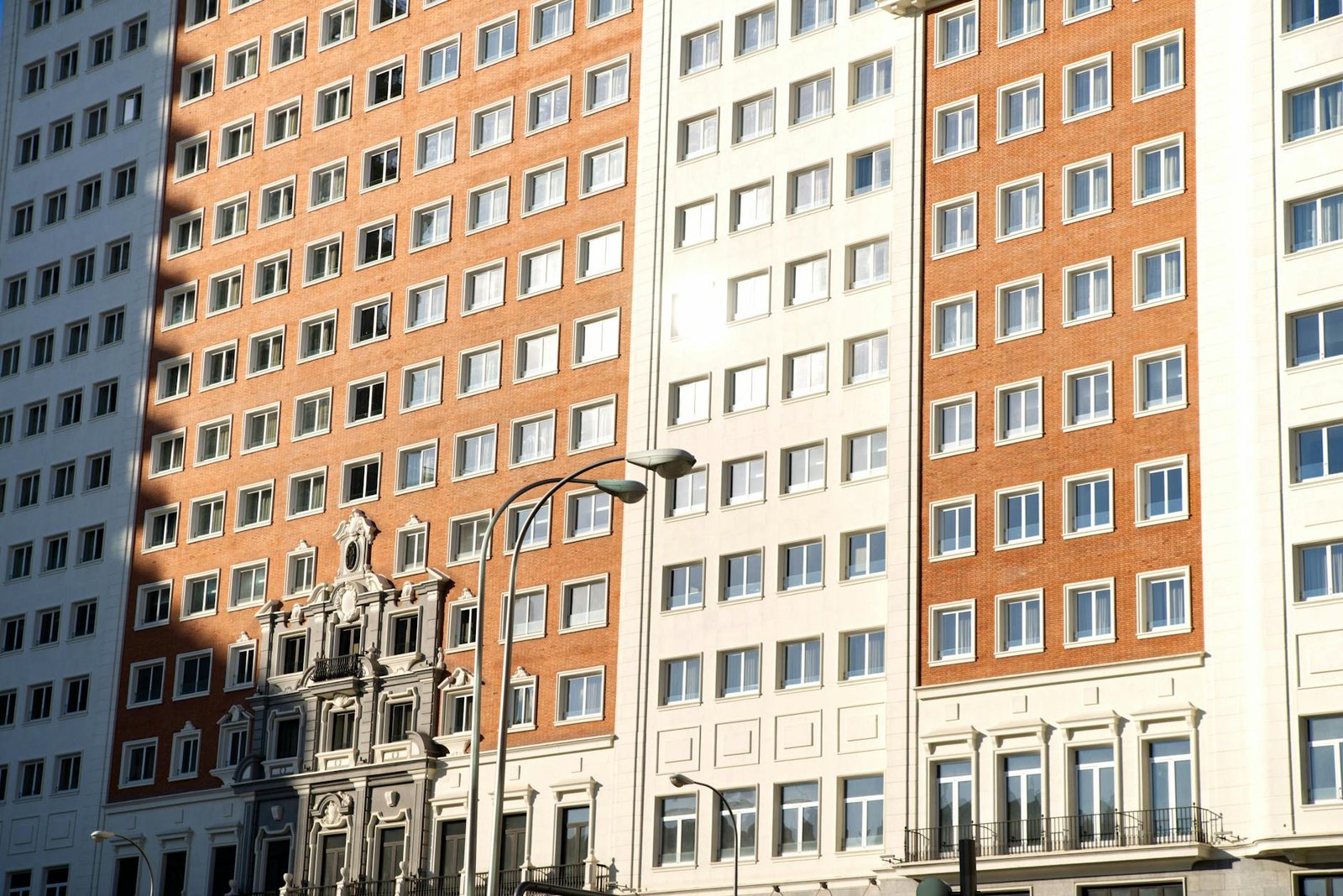 Sunlit facade of a classic residential building with windows in Madrid, Spain.