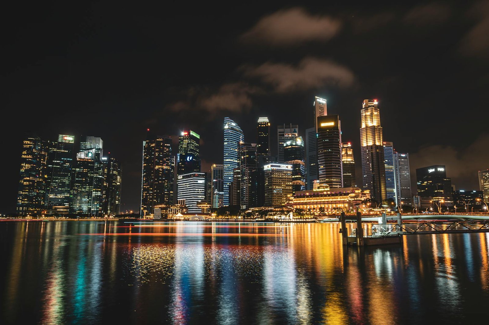 Dazzling night view of Singapore's illuminated skyline reflecting on water, showcasing modern skyscrapers.