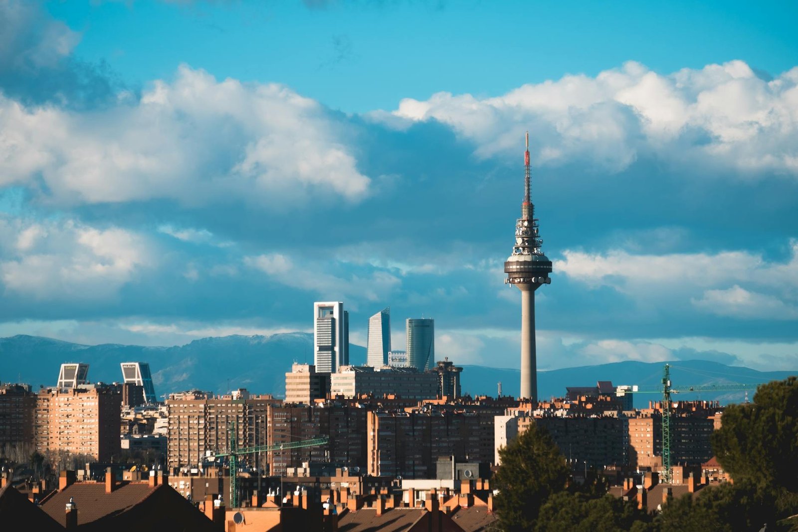 Skyline of Madrid featuring the iconic Torre España and modern skyscrapers against a cloudy sky.